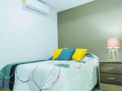 a bedroom with a bed with yellow and blue pillows at Malecon Cozy - Premium Plus 10 in Santo Domingo