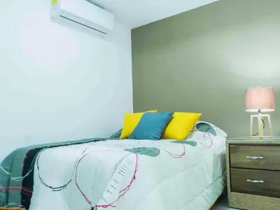 a bedroom with a bed with yellow and blue pillows at Malecon Cozy - Premium Plus 11 in Santo Domingo