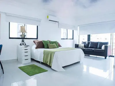 a white bedroom with a bed and a couch at Malecon Cozy - Premium Plus 11 in Santo Domingo