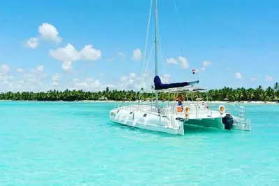 a white boat in the water next to a beach at Beautiful Apt Dominicus Bayahibe, Walk To Beach! in La Laguna