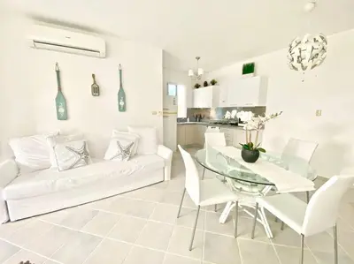 a white living room with a glass table and white chairs at Beautiful Apt Dominicus Bayahibe, Walk To Beach! in La Laguna