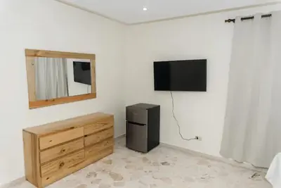 a room with a television and a dresser and a dresser with a mirror at Verde Bonavita in Santiago de los Caballeros
