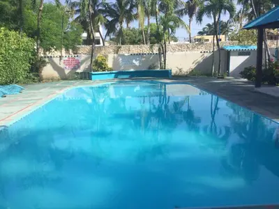 a large pool with blue water in a yard at La Gaviota A3 in Juan Dolio