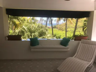 a window with a white bench and a chair in a room at La Gaviota A3 in Juan Dolio
