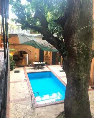 a swimming pool with a tree next to a house at Mansion Colonial Boutique Hotel Pool Jacuzzi Bar Restaurant by BTC Group Crypto in Santo Domingo