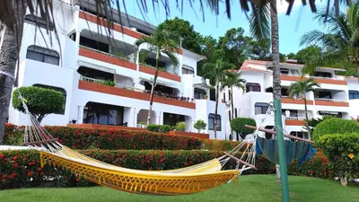 a hammock in a park in front of a building at The biggest swimming pool in Sosua, frente a la piscina más grande en sosua in Sosúa