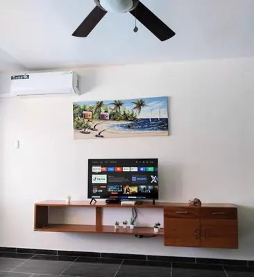 a living room with a tv and a ceiling fan at The biggest swimming pool in Sosua, frente a la piscina más grande en sosua in Sosúa