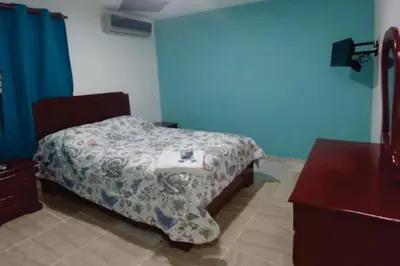 a bedroom with a bed and a dresser in it at Hostal Magisterial Santo Domingo in Santo Domingo
