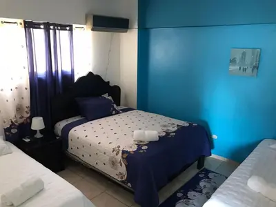 a bedroom with two beds and a blue wall at Hostal Magisterial Santo Domingo in Santo Domingo