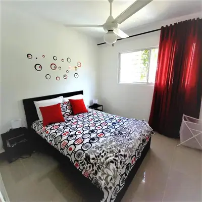 a bedroom with a bed with red pillows and a ceiling at Your Space piscina, parque infantil, 3 habitaciones , Res Breezes Santiago in Santiago de los Caballeros