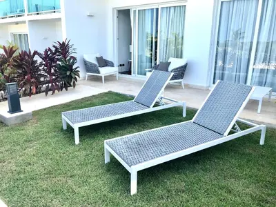 three chairs sitting on the grass on a patio at Apartamento Acceso Directo a la piscina A-108, A-120, A-117 y B-137 in Punta Cana