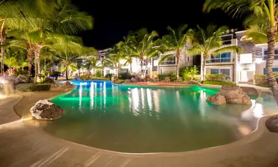 a pool at night with palm trees and buildings at Apartamento Estrella Dominicus in La Laguna