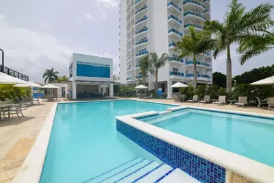 a swimming pool at a resort with a large building at Elegante Blue Marine Apartamento Juan Dolio in Juan Dolio