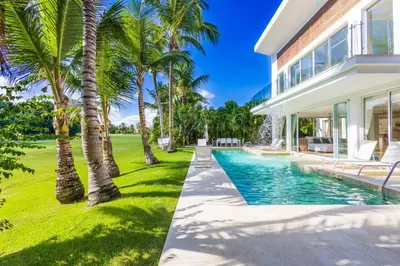an exterior view of a house with a swimming pool and palm trees at Luxury Rentals in Punta Cana - Exclusive Waterfall Villa with Private Pool, BBQ, Maid, Golf in Punta Cana
