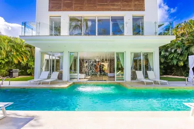 a house with a swimming pool in front of a house at Luxury Rentals in Punta Cana - Exclusive Waterfall Villa with Private Pool, BBQ, Maid, Golf in Punta Cana
