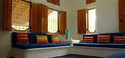 a room with blue couch with colorful pillows and windows at Villa directly on the beach, las Ballenas in Las Terrenas