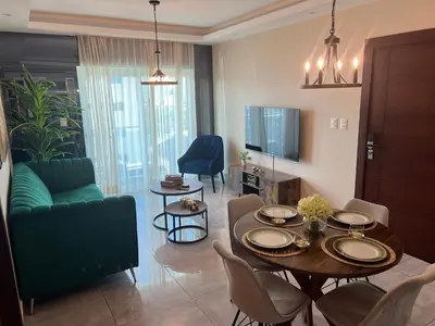 a living room with a table and a green couch at Amazing Rooftop and Best View of the City in Santiago de los Caballeros