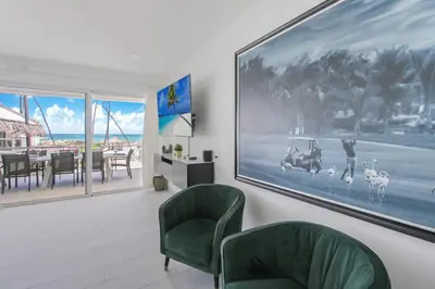 a living room with two green chairs and a painting on the wall at Luxury Villa in Bávaro Just on the Beach in Punta Cana