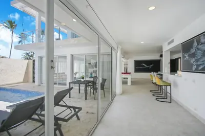 a living room with glass walls and a table and chairs at Luxury Villa in Bávaro Just on the Beach in Punta Cana