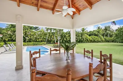 a dining room with a table and a pool at Amazing Villa in Casa de Campo with Included in Price Maid and Waiter in La Romana