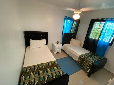 two beds in a room with blue curtains at Santiago City Center Huge nice Apartment to stay rooftop to enjoy the city view in Santiago de los Caballeros