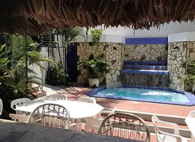 a pool with a table and chairs and a fountain at Hotel Caribe in Santa Cruz de Barahona