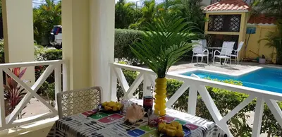 a table with a vase on a balcony with a pool at Vanilla House in Bayahibe