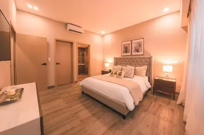 a bedroom with a large bed and a table with lamps at Fully Serviced Apartment at Regatta Living - 2C in Santo Domingo
