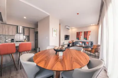 a dining room and kitchen with a wooden table and chairs at Fully Serviced Apartment at Regatta Living - 3B in Santo Domingo
