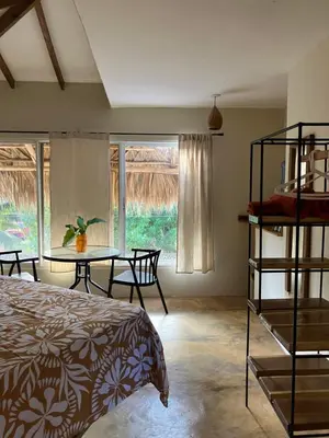a bedroom with a bed and a table and chairs at Yes Papa! Rooms only 100m from the beach! in Las Galeras