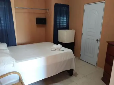 a bedroom with a white bed and a refrigerator at Apartahotel Next Nivel - Queen room with Ac in Punta Cana