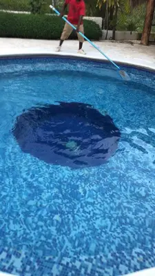 a person holding a broom in a pool of blue water at VILLA CAMPESTRE EN LOMAS LINDA in Villa Altagracia