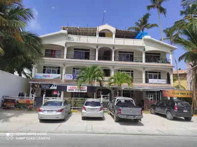 a white building with cars parked in front of it at Private Study Punta Cana in Punta Cana