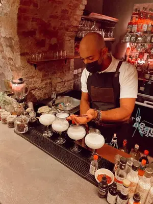 a man in a kitchen preparing drinks in glasses at Mosquito Boutique Hotel Zona Colonial in Santo Domingo