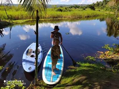 two boys are standing on a paddle board in the water at Method Living Tropical Edition 50024 in Cabarete