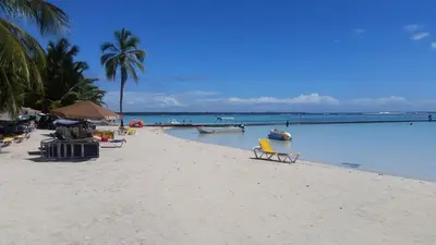 a beach with chairs and boats in the water at Hotel Casa Coco in Boca Chica