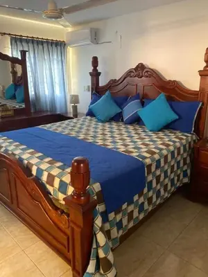 a bedroom with a large wooden bed with blue pillows at Cerro Altos jardin 809-488-8618 in Santiago de los Caballeros