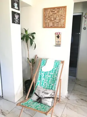 a rocking chair in a room with a plant at En el corazón de la romana con a/c, wifi, luz y gas incluido. in La Romana
