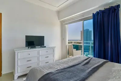 a bedroom with a bed and a tv and a window at Sunset View 2BR Apartamento Juan Dolio Las Velas in Juan Dolio