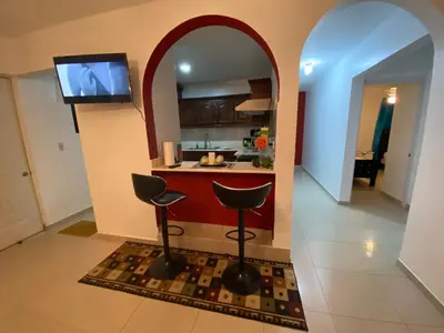 a kitchen with a bar with two stools and a tv at 6A Cozy Apt in Santiago Center - Great Stay in Santiago de los Caballeros