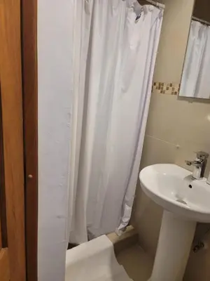 a bathroom with a white shower curtain and a sink at small apartment in Santo Domingo
