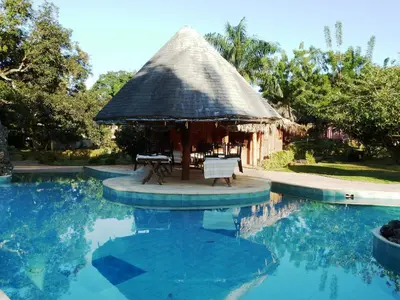 a hut with a table and chairs next to a swimming pool at Las Puertas del Paraíso in Río San Juan