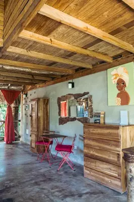 a dining room with a table and two red chairs at Bungalows India, El Valle, Samana in Santa Bárbara de Samaná
