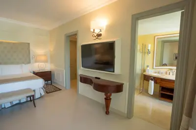 a bedroom with a bed and a television and a bathroom at JOIA Bavaro by Iberostar - Adults Only All Inclusive Resort in Punta Cana