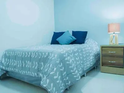 a blue bedroom with a bed and a night stand at Malecon Cozy Private Room in Santo Domingo