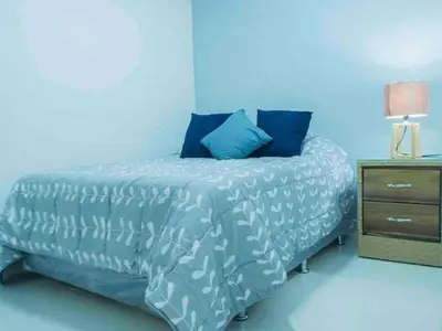 a blue bedroom with a bed and a night stand at Malecon Cozy Private Room in Santo Domingo