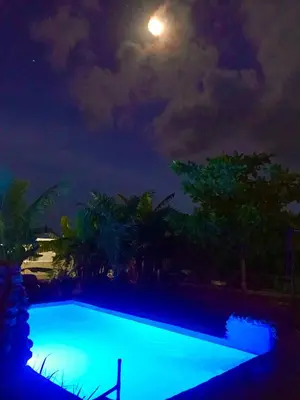 a swimming pool at night with the moon in the sky at ECOVILLA CORAL GARDEN in Baoruco
