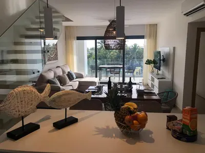 a living room with a table with a bowl of fruit at Hermoso Penthouse a solo pasos de la Playa in Punta Cana