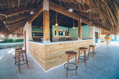 a bar with stools in front of a bar with wooden walls at Iberostar Selection Bavaro Suites - All Inclusive in Punta Cana