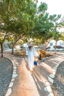 a woman walking down a path with a hat at Punta Rucia Lodge Hotel Boutique & Spa in Punta Rucia
